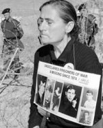 A grieving mother holding photos of her missing son.